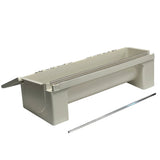 A white, rectangular plastic poultry feeder with raised ends, a detachable lid partially open on one side, and a metal rod placed in front of it. Similar to an NSF approved KenKut II dispenser, its smooth design stands out against a plain white background.