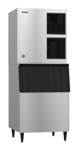 A tall, stainless steel Hoshizaki cube-style ice maker features two black ventilation panels on the upper front and a large black ice bin door below, standing on four sturdy black legs against a white background.