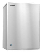 A large, stainless steel Hoshizaki ice maker with a smooth, flat front and sharp edges. The Hoshizaki logo is on the upper left, and a round blue certification badge is near the bottom left. It produces clear crescent cube ice and has a minimalist reflective surface.