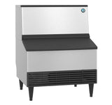 A commercial ice maker with a stainless steel finish, black top panel, vented black bottom section, and four sturdy legs. The Hoshizaki KM-301BAJ produces crescent style cube ice and features a logo at the top right corner—ideal for restaurants or large kitchens.