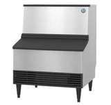A Hoshizaki commercial ice maker with a stainless steel body, black vented front panel, raised black legs, and a top bin with a black lid. This cube-style machine features a small round logo and is ideal for food service environments.