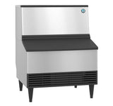 A commercial stainless steel ice maker with black legs and vented front panel. The machine features a sloped black top, a blue logo on the upper right, and produces crescent style cubes—ideal for restaurants or cafeterias. ADA compliant design.