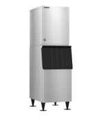 A tall, stainless steel commercial Ice Maker with a boxy top unit and lower storage bin. The bin has a black, angled door for Crescent Cube ice access. The machine stands on four black legs and features a modern, industrial design.