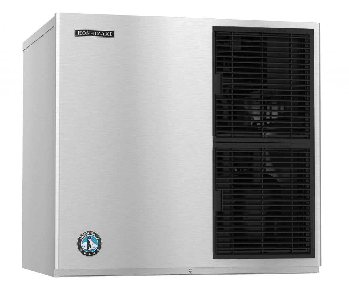 A stainless steel Hoshizaki ice maker with a cube-style design features two black vented sections on the front panel and a round blue and white penguin logo on the lower left, giving it a sleek, industrial look.