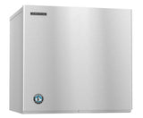 A stainless steel, box-shaped commercial ice maker with a smooth surface. The Hoshizaki logo appears at the top left, and a round blue-and-white penguin emblem is near the bottom. Features a minimalist design and produces crescent cube ice.