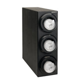 A black rectangular wall-mounted dispenser, also suitable for countertop use, holds three stacked rolls of white tape behind transparent round covers. The unit has a matte finish and is labeled DISPENSE-RITE at the top right corner.