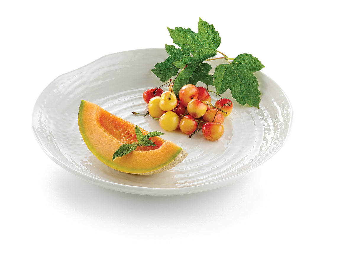 A white Frostone Collection tray holds a cantaloupe wedge garnished with a mint sprig and a small bunch of yellow and red cherries still attached to leafy stems, all set on a clean white background.
