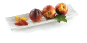 Three whole nectarines and three nectarine slices are arranged on a long, rectangular serving dish. One nectarine has green leaves attached. The fruit is glossy with red, orange, and yellow tones against a plain white background.