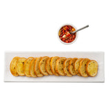 A rectangular serving dish from the Frostone Collection displays 13 slices of toasted baguette in a row, with a small white bowl of tomato bruschetta and a metal spoon above, all set against a clean white background.