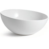A plain, smooth white melamine bowl from the Sierra Melamine Collection sits on a white surface, photographed at an angle that highlights its round, deep interior and slightly glossy finish. This dishwasher safe bowl casts a soft shadow to the left.