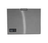 A stainless steel ice machine panel with a smooth, reflective surface. The top center features the Scotsman logo, while the bottom left displays a black control panel, indicating it’s part of the Prodigy ELITE Ice Maker series. The background is plain white.
