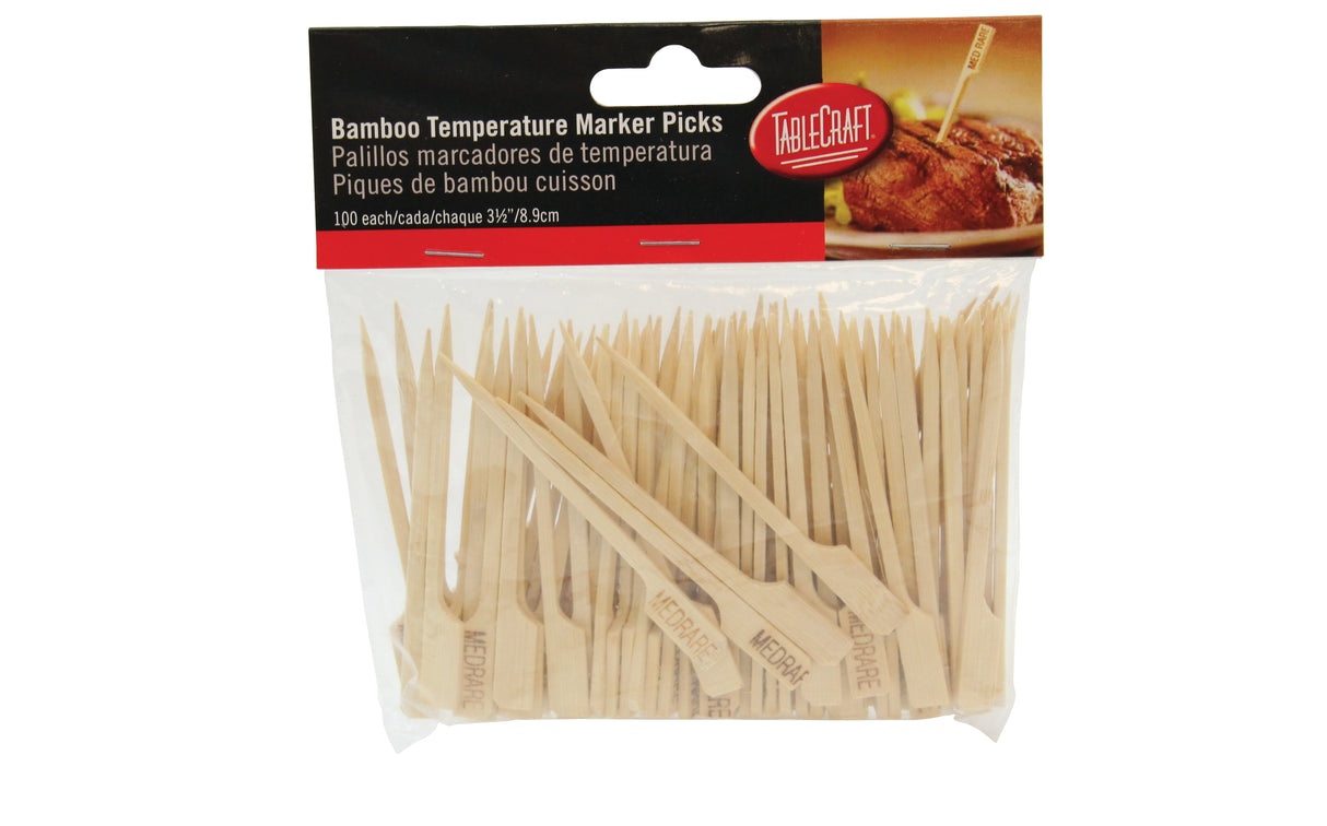 A plastic bag containing 100 bamboo meat marker picks, each labeled “MED RARE” for medium rare steaks. The TableCraft-branded bag features a photo of a steak with a pick inserted.