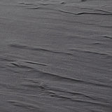 A close-up view of a gray melamine surface with visible, slightly uneven, wavy lines and subtle wrinkles, resembling crumpled fabric or a textured plastic sheet—perfect for a display tray that’s both stylish and dishwasher safe. The lighting highlights the contours.