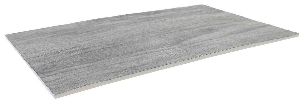 A rectangular, thin, gray sheet with a subtle wood grain texture, reminiscent of a Frostone Collection Serving Tray, is viewed from an angle against a white background. The material appears smooth and slightly reflective, with uneven, natural-looking edges.