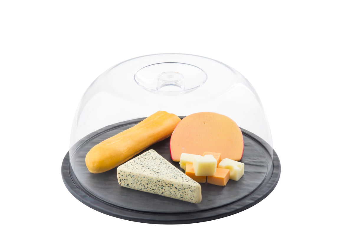 A round black melamine display tray with assorted cheeses—wedge of herb cheese, block of orange cheese, cheese stick, and cubes—covered by a clear plastic dome, displayed against a white background.