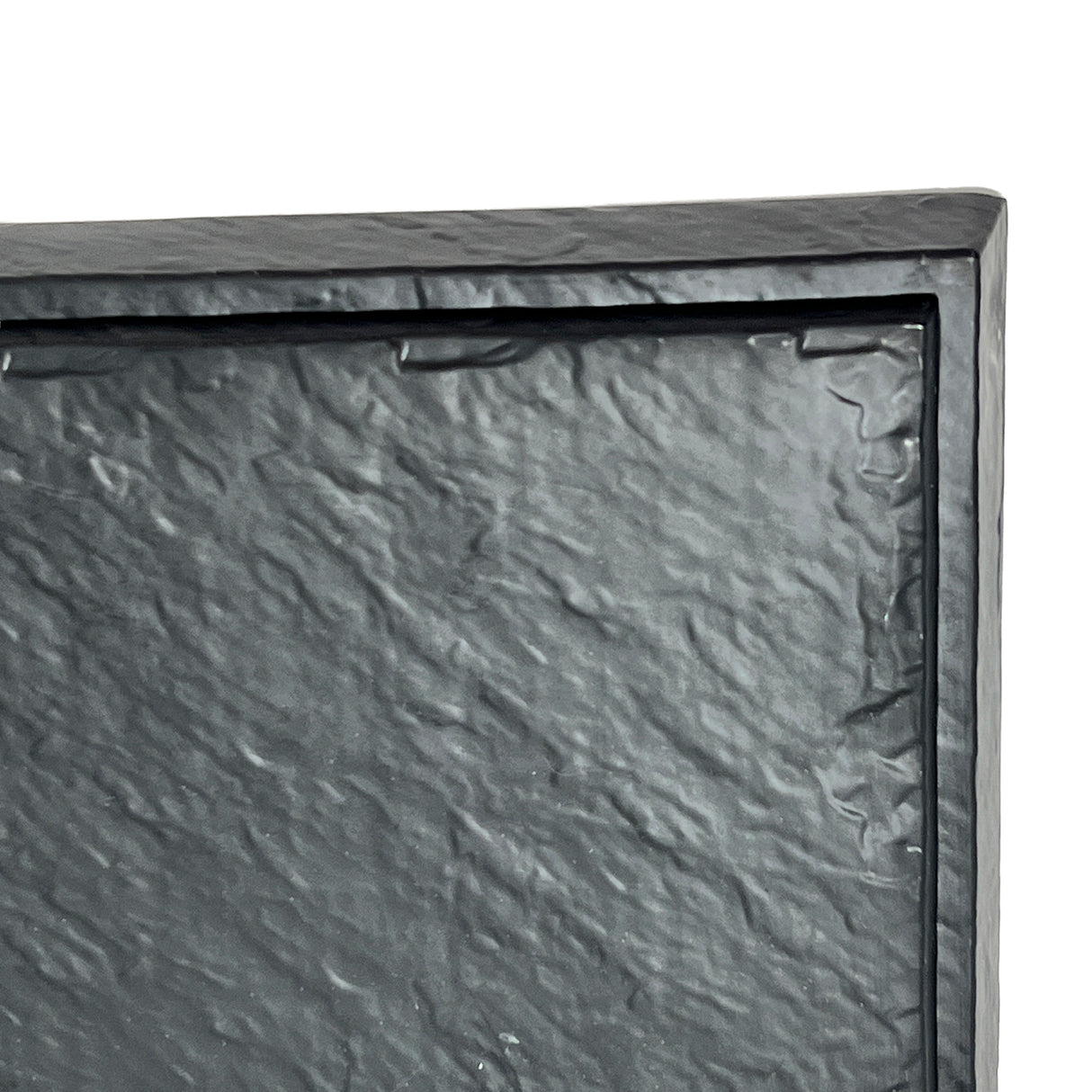 A close-up of a black, textured rectangular surface with a raised border. This Frostone Collection Display Tray, made from break resistant melamine, shows only the upper left corner of the tray against a white background.
