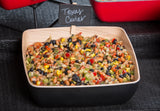 A square Frostone Naturals melamine bowl from TableCraft Products holds vibrant Texas caviar—a colorful bean salad of black beans, corn, peppers, and herbs. A small chalkboard sign labeled “Texas Caviar” is clipped to the bowl’s edge.