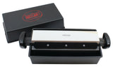 A rectangular black box with a red TableCraft logo contains a medium-grit sharpening stone set in a black holder with handles, positioned above a black tray. Part of the Three-Way Sharpener System, it offers different sharpening settings for knives.