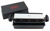 A rectangular black box with a red TableCraft logo contains a medium-grit sharpening stone set in a black holder with handles, positioned above a black tray. Part of the Three-Way Sharpener System, it offers different sharpening settings for knives.