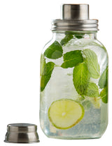 A 14 oz Mason Jar Cocktail Shaker filled with clear liquid, ice cubes, fresh mint leaves, and a lime slice. The stainless steel lid is screwed on, while the matching cap rests beside the jar against a plain white background.