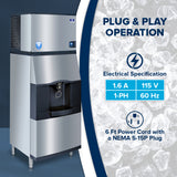 A commercial vending ice dispenser with a cup beneath the touchless lever is shown. Text beside it reads: Plug & Play Operation, listing specs—1.6 A, 115 V, 1-PH, 60 Hz, plus a 6-foot power cord with NEMA 5-15P plug—on an ice background.
