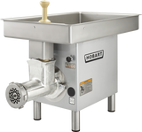 A commercial Hobart Meat Grinder with a 3 HP motor, large stainless steel pan, round grinding head, and tan plastic pusher. The unit stands on four sturdy metal legs and features branding, warning labels, and a side power switch.