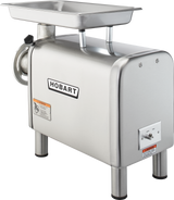 A bench type Hobart Meat Chopper with a 1/2 HP motor, stainless steel rectangular body, sturdy legs, metal tray on top, side grinding exit, visible safety labels, and the Hobart logo centered on the front.