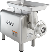 A stainless steel Hobart meat chopper with a 1/2 HP motor features a rectangular tray on top, a cylindrical grinding mechanism at the front, and four sturdy legs. The bench type design displays the Hobart logo and a caution label near the front.