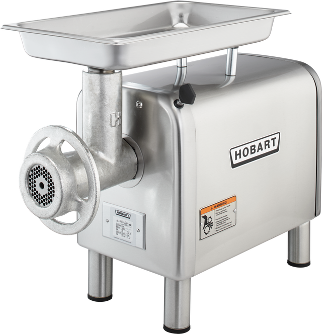 A stainless steel Hobart Meat Chopper with a 1/2 HP motor features a rectangular tray on top, cylindrical grinding mechanism, mesh grinder plate, labeled warning sticker, and four metal legs—perfect as a bench type unit for heavy-duty food processing.