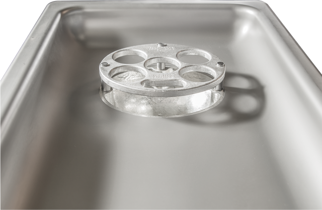 A close-up view of a shiny stainless steel Hobart commercial kitchen sink, focusing on a metal drain cover with four circular holes. The clean surface reflects light, and the drain cover casts a shadow inside the basin.