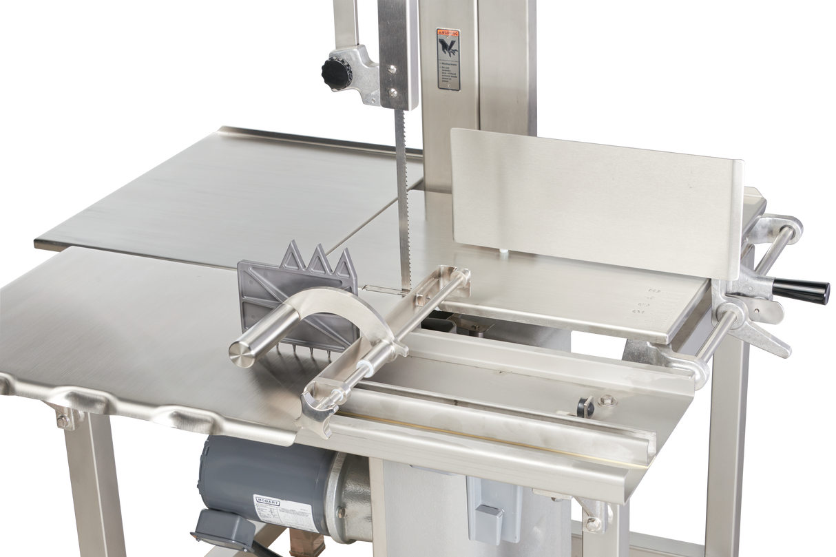 A close-up of a stainless steel Hobart 6801-18IP meat cutting bandsaw. The image highlights the sharp vertical saw blade, flat cutting table, integrated pusher, adjustable fence, safety guard, handle, and visible motor underneath.