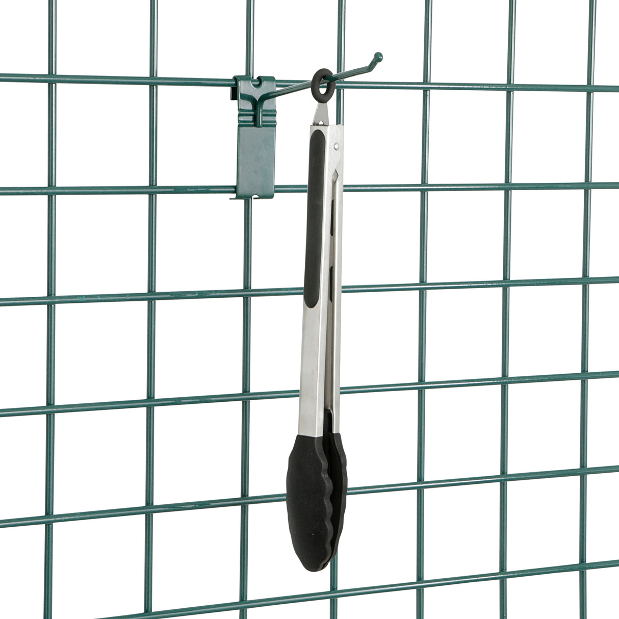 A pair of metal kitchen tongs with black silicone tips hangs from a SmartWall Prong Hook attached to a green wire grid panel. The grid has a rectangular pattern, and a small green clip is also attached above the tongs on the panel.