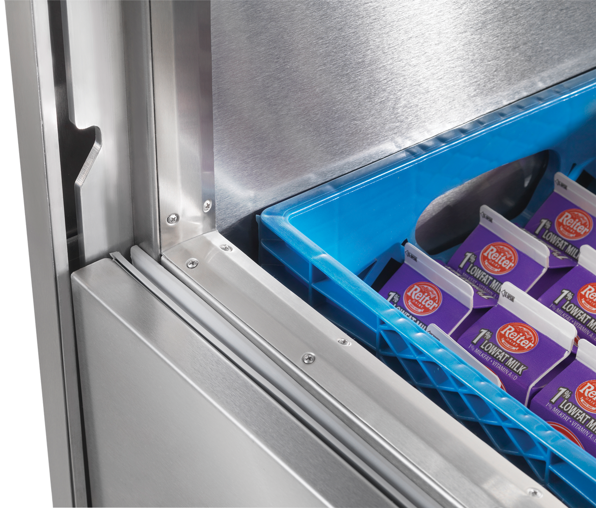 Close-up of a Traulsen milk cooler, partially open, revealing a blue plastic crate filled with cartons of Petal 1% lowfat milk inside. The image highlights the clean metal interior and the edge of the door.