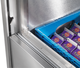 Close-up of a Traulsen milk cooler, partially open, revealing a blue plastic crate filled with cartons of Petal 1% lowfat milk inside. The image highlights the clean metal interior and the edge of the door.