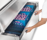 A person opens a refrigerator drawer, reaching into the double access milk cooler, which uses forced-air technology to keep dairy products fresh.