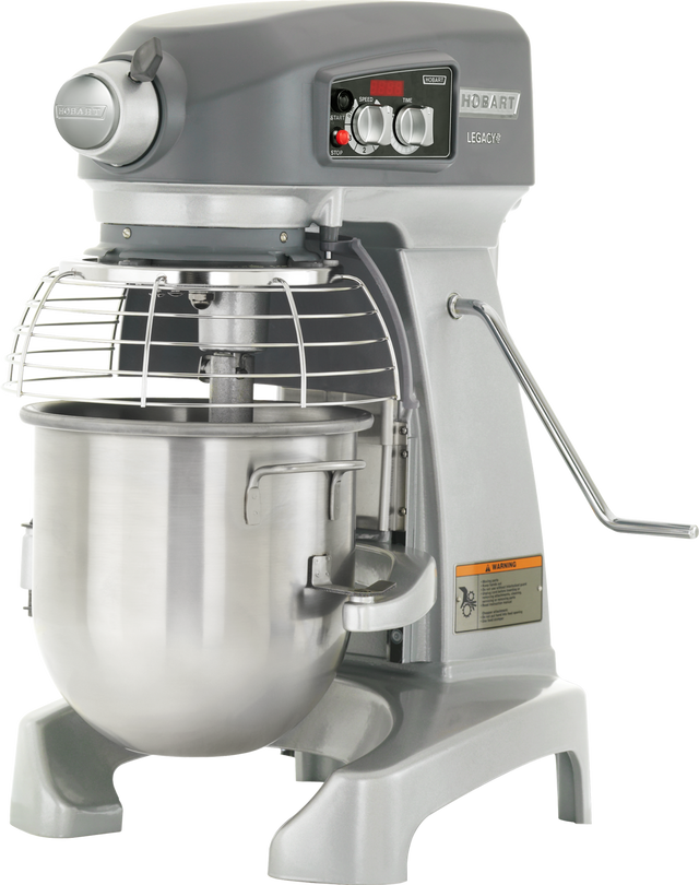 A large 12 quart planetary mixer with a stainless steel mixing bowl, metal guard, and control panel with dials and switches. The metallic gray Hobart bench mixer stands on sturdy legs with a side lever and warning label.