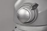 Close-up of a metallic Hobart planetary mixer head with a shiny round knob displaying the brand name “Hobart” in raised letters. A black lever extends from the side. The smooth, brushed finish stands out against a plain gray background.
