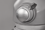 Close-up of a metallic Hobart planetary mixer head. The image focuses on the brand name Hobart embossed on a round knob, with a small black lever above it. The smooth, matte gray surfaces suggest its part of a 20 quart bench mixer.