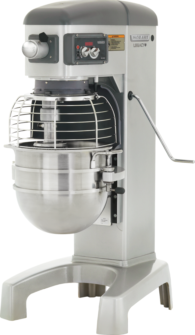 A large, industrial Legacy Planetary Mixer with a 30 qt metal bowl, protective wire guard, and control panel featuring knobs and buttons. The machine is grey and silver, with sturdy legs and a side lever for adjusting the mixing bowl’s height.