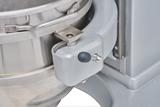 Close-up of a Legacy Planetary Mixer showing a large stainless steel mixing bowl secured with a metal latch and hinge mechanism. The mixer has a grey, sturdy frame with a black knob and lever for locking the bowl in place.