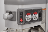 Close-up of a metallic industrial mixer control panel, part of the Hobart HL600C Legacy Correctional Planetary Mixer, with black, red, and silver buttons and dials. START/STOP buttons, speed/time knobs with digital displays, and a safety lever are visible.