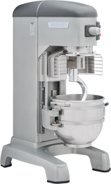 A large, industrial Hobart Legacy Planetary Mixer with a silver metal body. It features a protective wire guard, control panel with buttons and dial, and a stainless steel 60 qt mixing bowl fitted with a dough hook attachment.