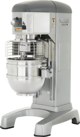 A large, industrial Hobart Legacy Planetary Mixer with a protective wire guard, control panel, and spacious stainless steel mixing bowl. This 60 qt mixer stands on a sturdy base, built heavy-duty for demanding commercial kitchen use.