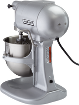 A silver Hobart N50A-10 planetary bench mixer with a metal mixing bowl and wire whisk attachment, viewed from the front right side. The mixer features a black power cord, visible warning label on the stand, and the Hobart logo on the body.