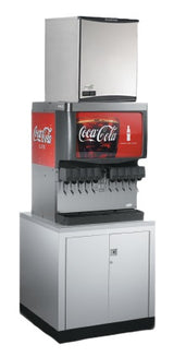 A commercial Coca-Cola soda fountain machine with multiple drink dispensers, a commercial ice machine on top producing chewable ice, and a lower cabinet for storage. The Coca-Cola logo stands out prominently on the bold red background.