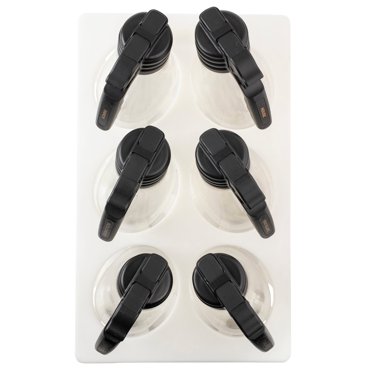 Six empty glass coffee carafes with black handles are arranged in two columns and three rows on a white rectangular tray, resembling a set of elegant salad dressing dispensers. The carafes’ handles all point toward the upper left corner.