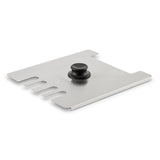 A rectangular stainless steel grill scraper with a black knob handle in the center, similar to a Waring deep fryer accessory. The left edge features five curved notches for cleaning grates; the opposite side has two square cutouts and straight edges. “Sur La Table” is visible.