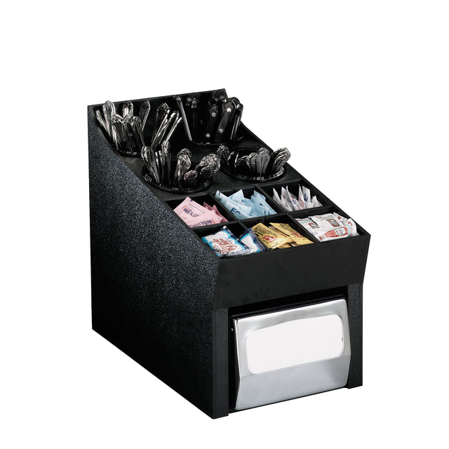 A black condiment organizer holds compartments of wrapped plastic utensils, napkins, and various packets of sweeteners and condiments. The front bottom section features a metal napkin dispenser. The background is plain white.