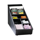 A black plastic condiment organizer holds stacked white stirrers, cappuccino mix packets, tea bags, sugar packets, and pink Sweet’N Low packets—each in its own compartment like a tidy straw organizer for easy access.