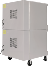 A large, rectangular commercial oven on wheels with air vents on the side and power cords attached. The double-deck electric oven features warning labels near the top and bottom corners. Its smooth, light gray surface adds to its industrial design.